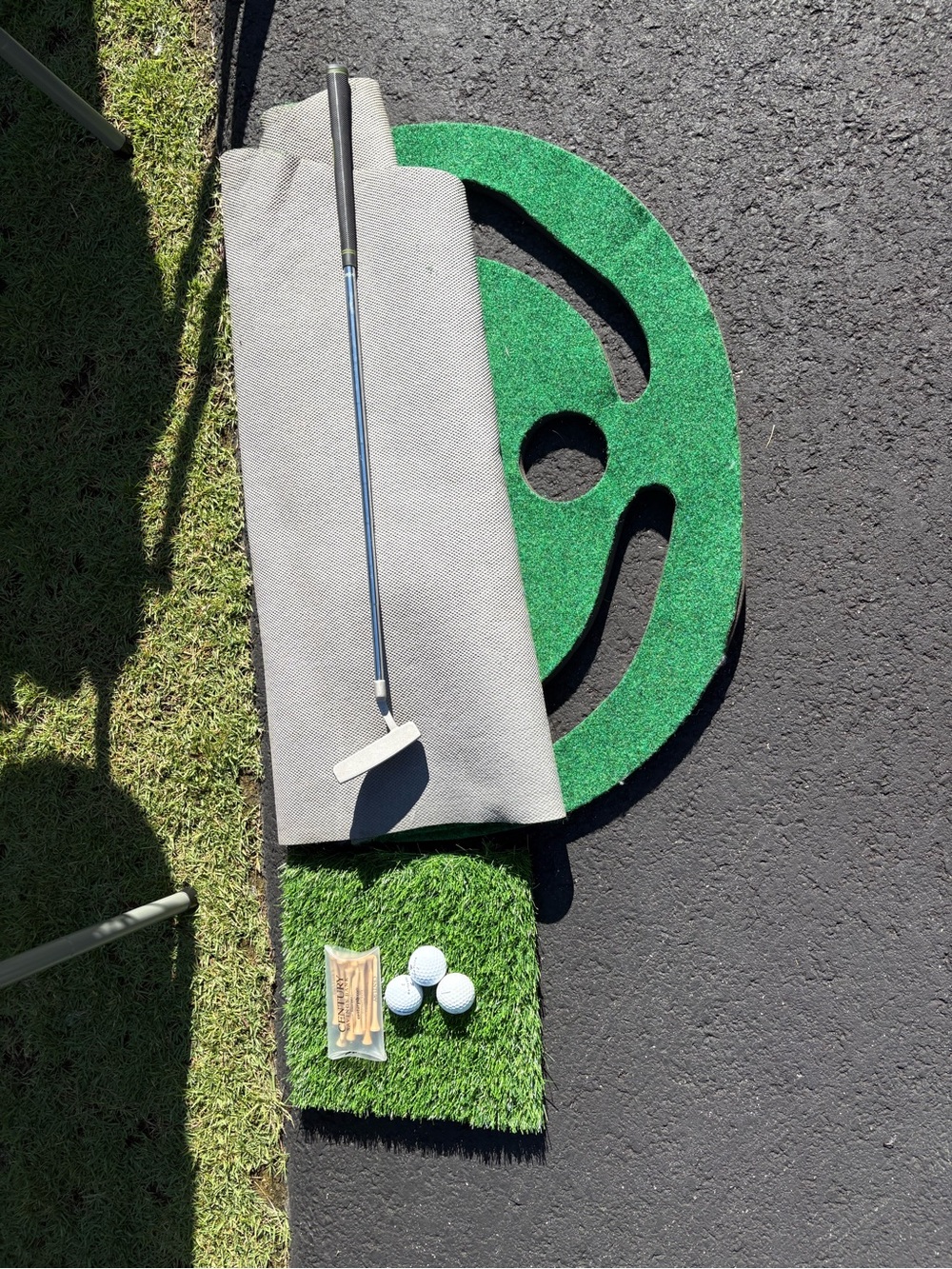 Portable Putting Green Mat with tees, golf balls, putter, and tee mat
